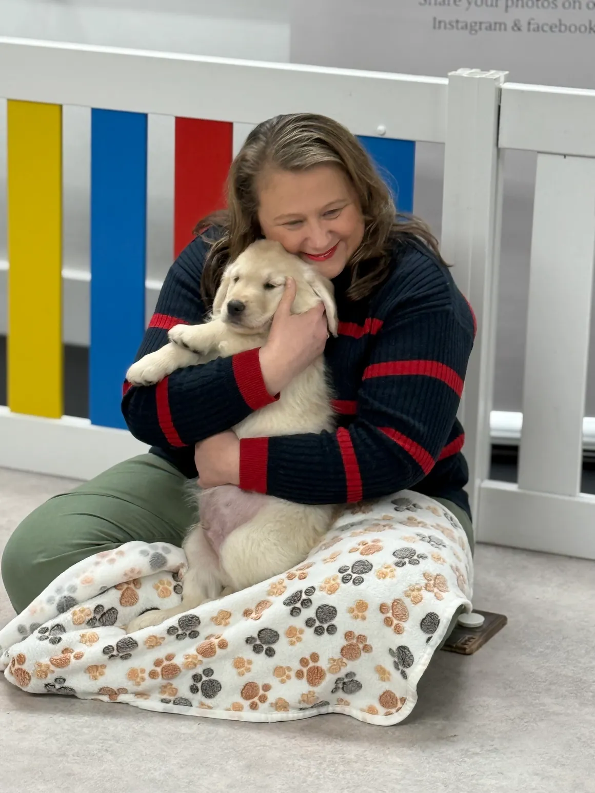 Woman cuddling a golden retriever puppy