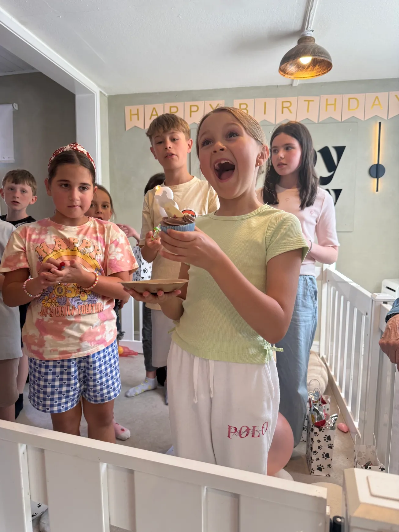 Excited girl holding birthday cupcakes